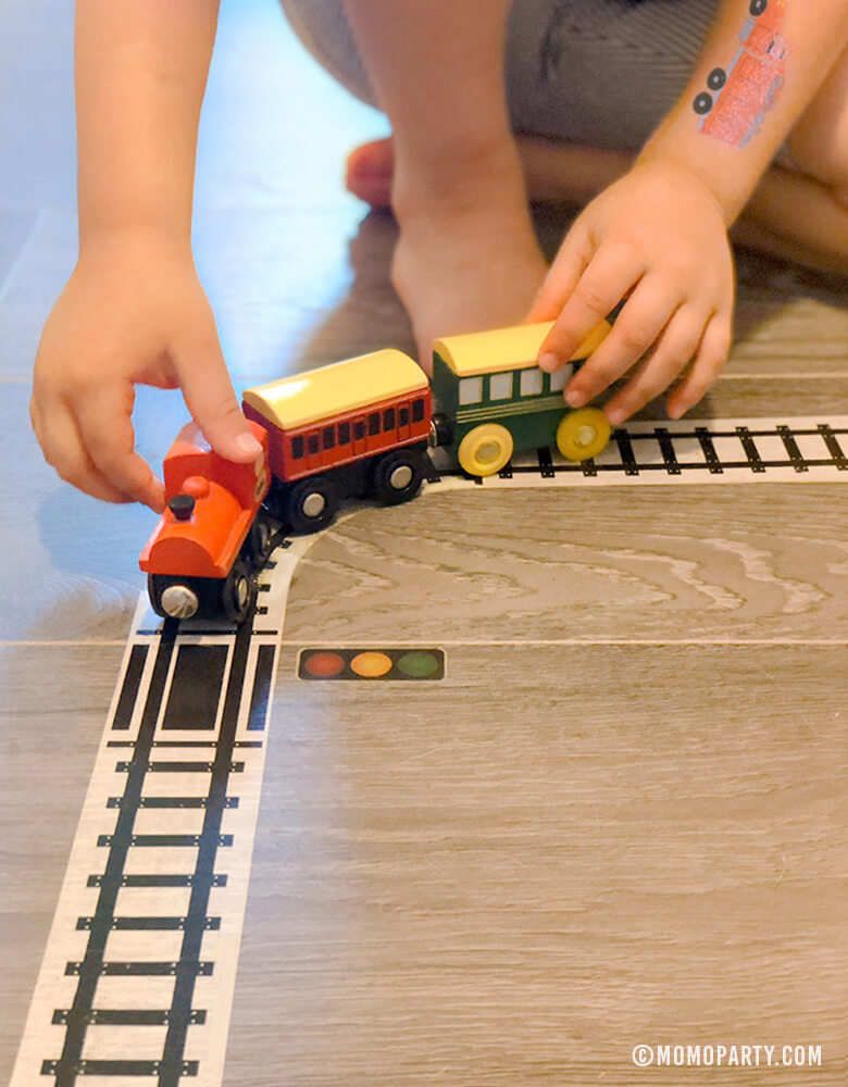 Kid play train wooden toy on Train Track Tape on the floor 