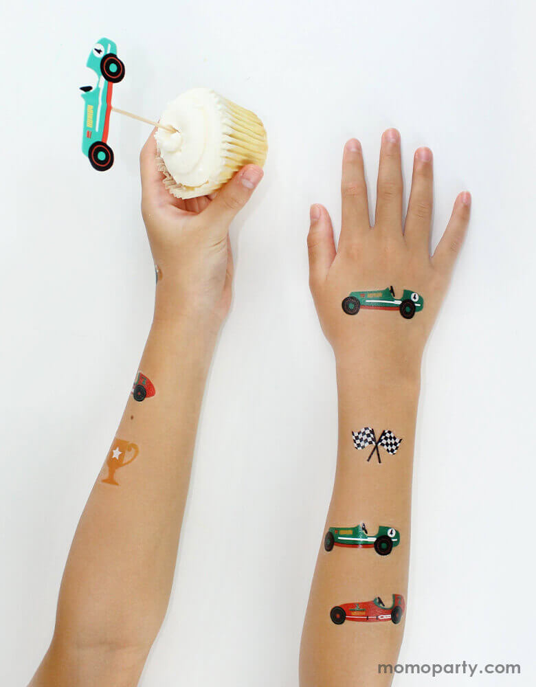 Kid hold a cupcake with Merilulu vintage race car topper, with showing his arm with Merilulu - Vintage Race Car Temporary Tattoos in 5 designs of Race cars, black and white checkered flags, trophy. These vintage race car temporary tattoos make perfect gift or party favors for your little race car fans, or car car party activities, race car party gift.