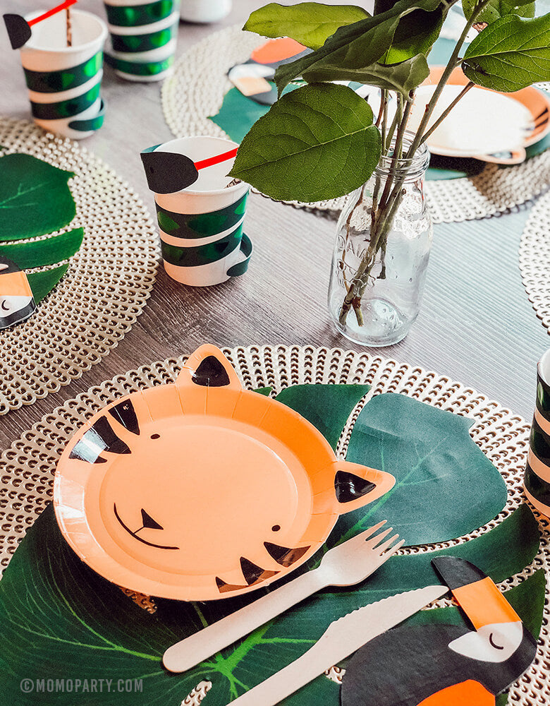 Safari Jungle Party ideas of Table decoration with tiger paper plates, toucan napkin, palm leaves as table mat, snake paper cups