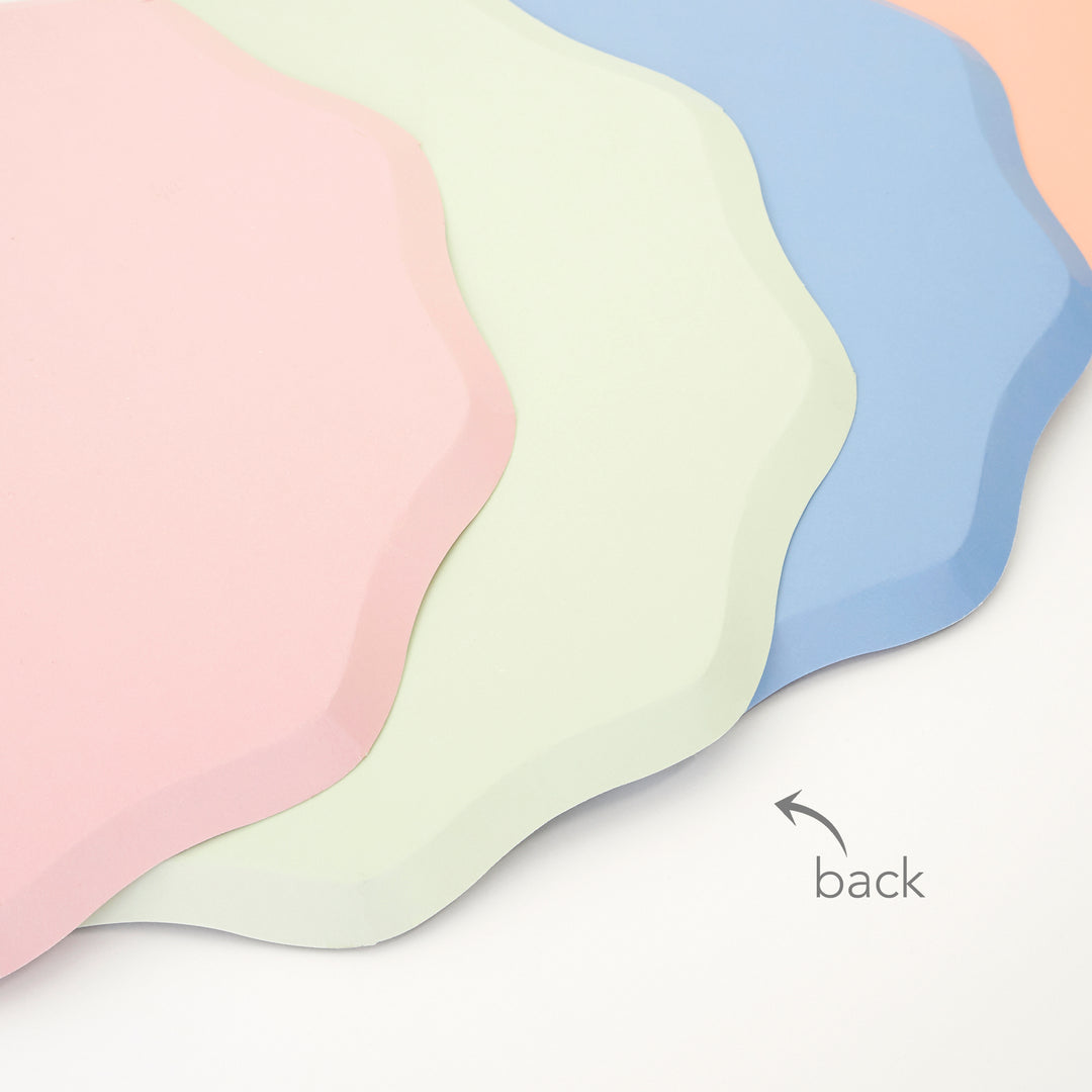 A Close up details of back of Ditsy Floral side Plates By Meri Meri. Features a solid 4 colors: blue, green, pink and peach with a stylish scalloped edged paper plates. Made from eco-friendly paper. Add a touch of springtime beauty to your party table with these high quality, well designed party plates.