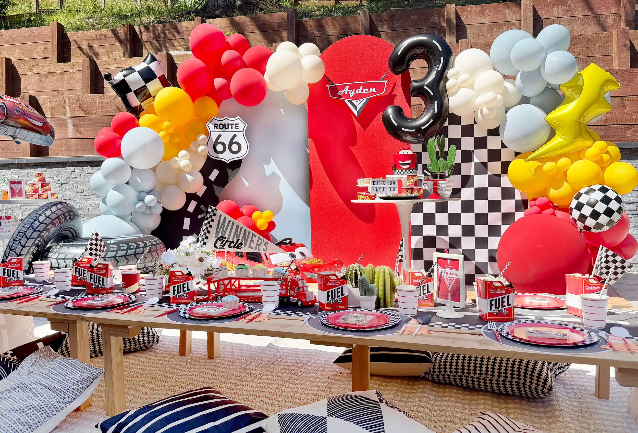 An adorable setup for a kid's Disney Cars Lightning McQueen themed birthday party styled by Momo Party featuring festive balloons, adorable table setting and fun decorations.