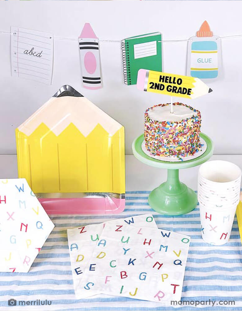 A school themed party table filled with Momo Party's school themed party supplies including a pencil shaped plate, ABC alphabet patterned napkins, plates and cups. Next to the tableware there's a cake topped with a pencil shaped cake topper with "Hello 2nd Grade". In the back there's a back to school party banner featuring colorful school themed pennants including crayon, glue bottle, notebook and more. All this makes a great inspo for a back to school party or first day of school celebration.