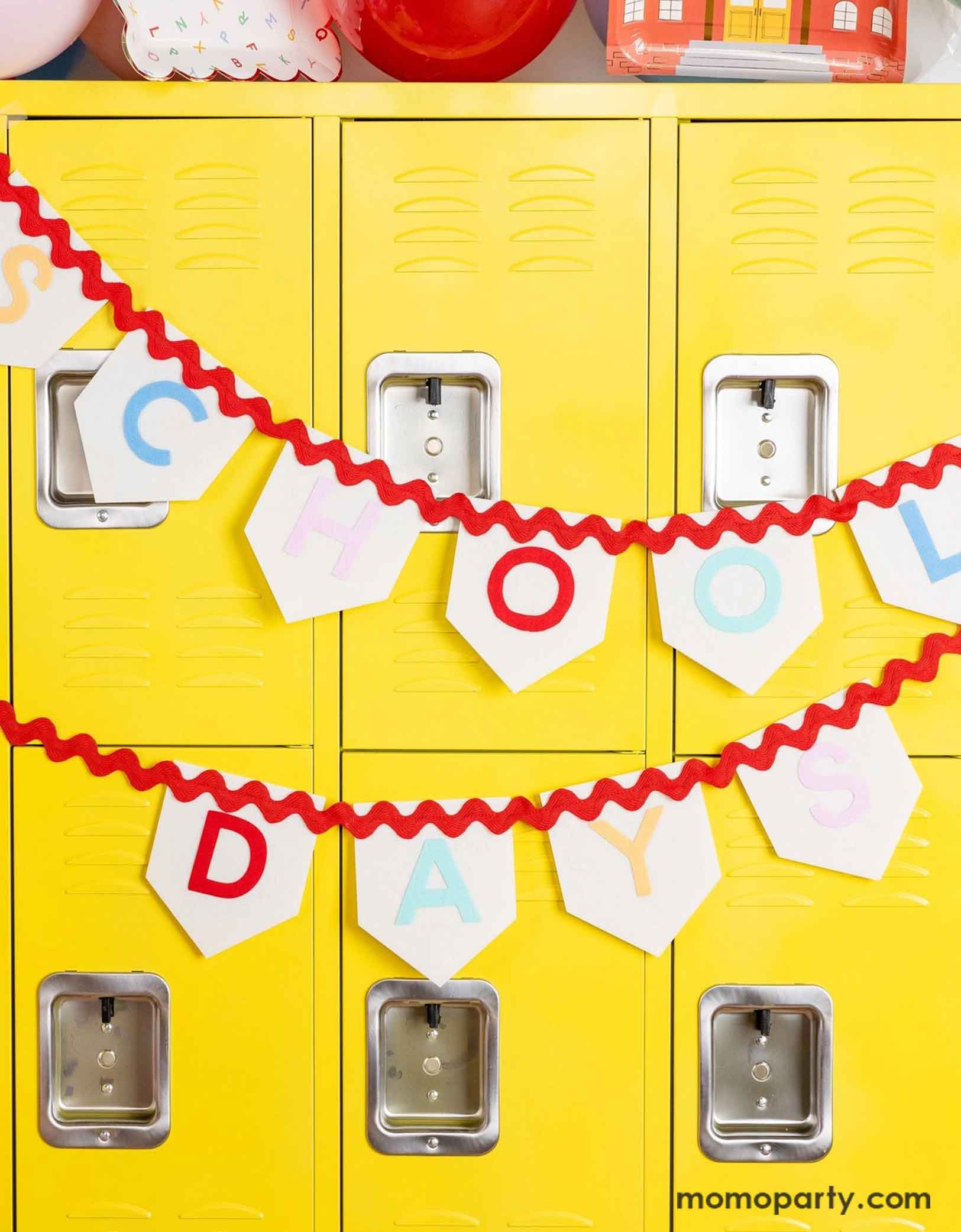 Momo Party's 6ft School Days Felt Banner by My Mind's Eye hung across a wall of yellow lockers at school. Made of high-quality felt material, this banner is perfect for creating a festive atmosphere for your back to school party or first day of school celebration. Hang it up to celebrate the start of a new school year or as a backdrop for your school-themed event.