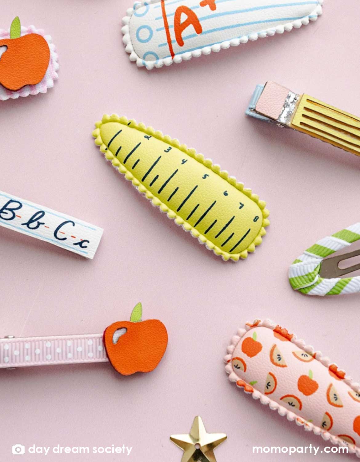 An overhead shot of Momo Party's Momo Party's Smarty Pants school themed Hair Clips by Daydream Society on a light pink background. The designs of these hair clips are inspired by school supplies, including alphabet letters A, B, and C, pencils, rulers, apple etc. These hair clips are perfect for back to school picture day, first day of school, and every school day in between.
