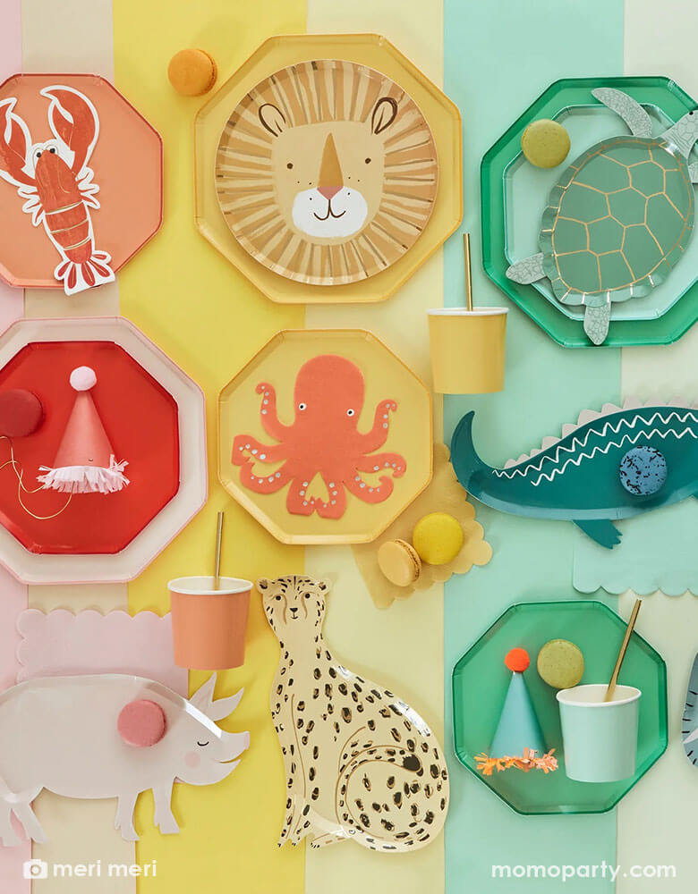 A rainbow colored table with party plates, cups, napkins hats and desserts arranged by colors of red, pink, yellow and green. Featuring Meri Meri plates, some in die-cut animal shaped including a lion, a pig, a cheetah, a lobster, a sea turtle, an alligator and an octopus, some in basic solid colors, in different sizes, mix and match them to create a happy celebration!