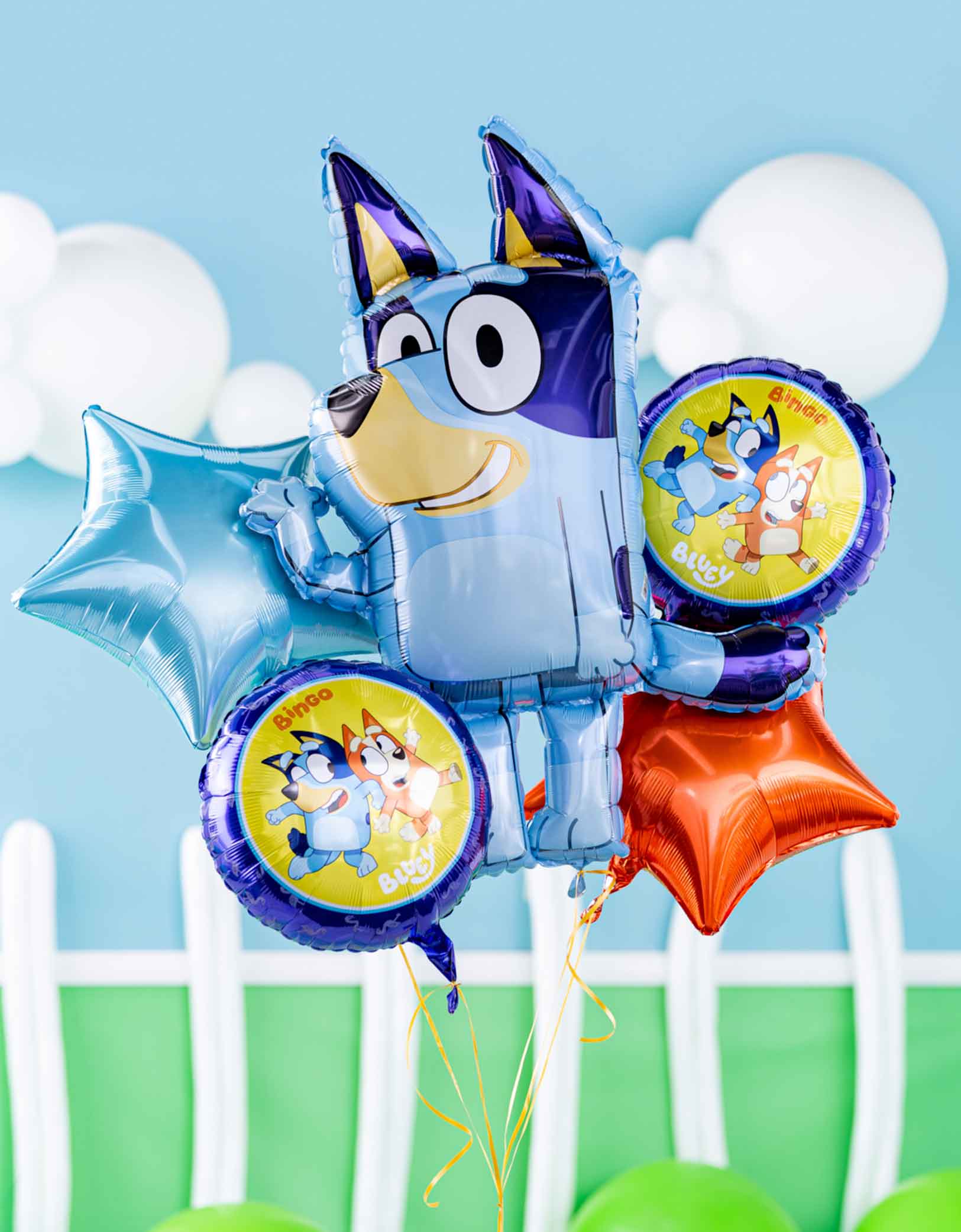 Bluey-themed balloon bouquet featuring 32" Bluey shaped foil balloon, 18 junior round Bluey and Bingo foil balloons and star shaped foil balloons in light blue and orange, floating with a blue sky with clouds background.