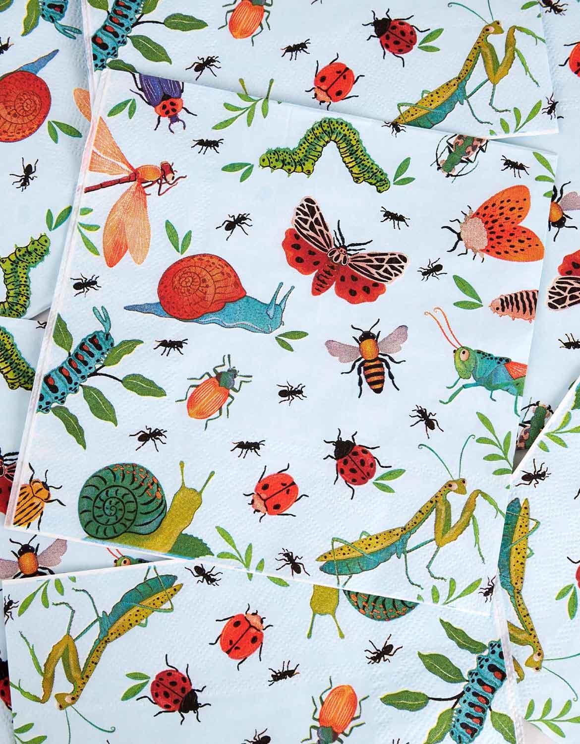 Multiple Momo Party's 6.5" light blue bug themed large napkins with colorful insects spread out on a table.