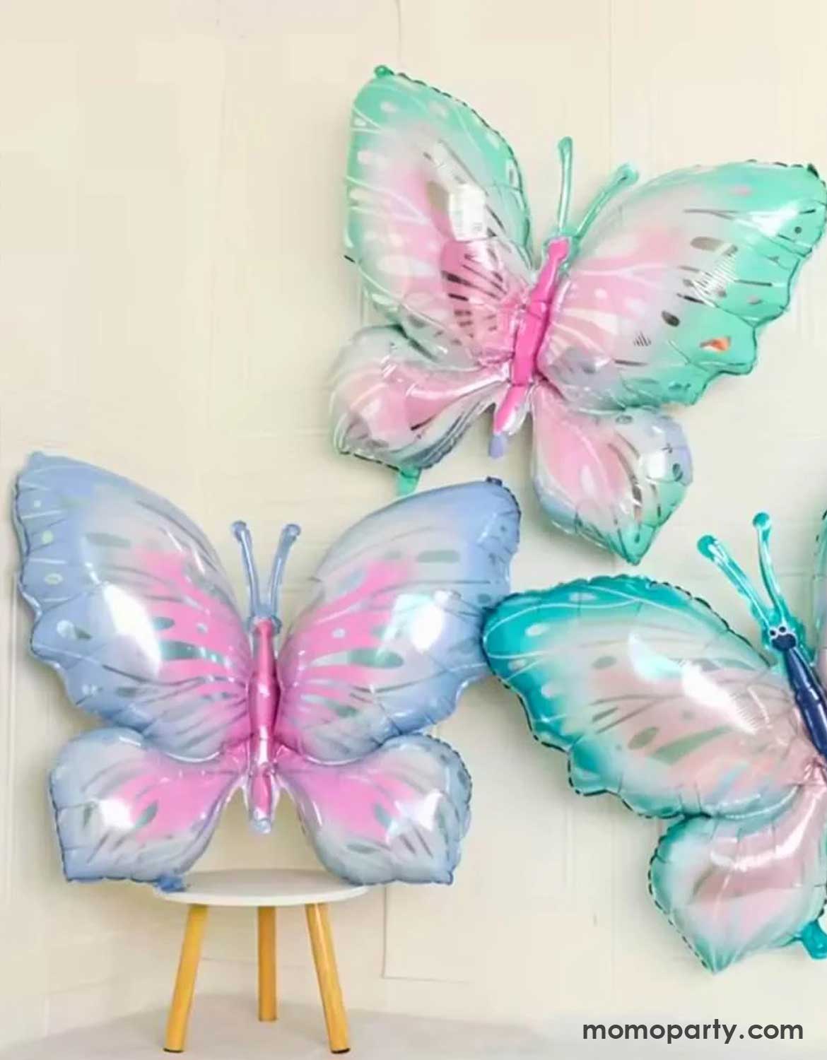 Three pastel-colored butterfly-shaped balloons from Momo Party on a white background.