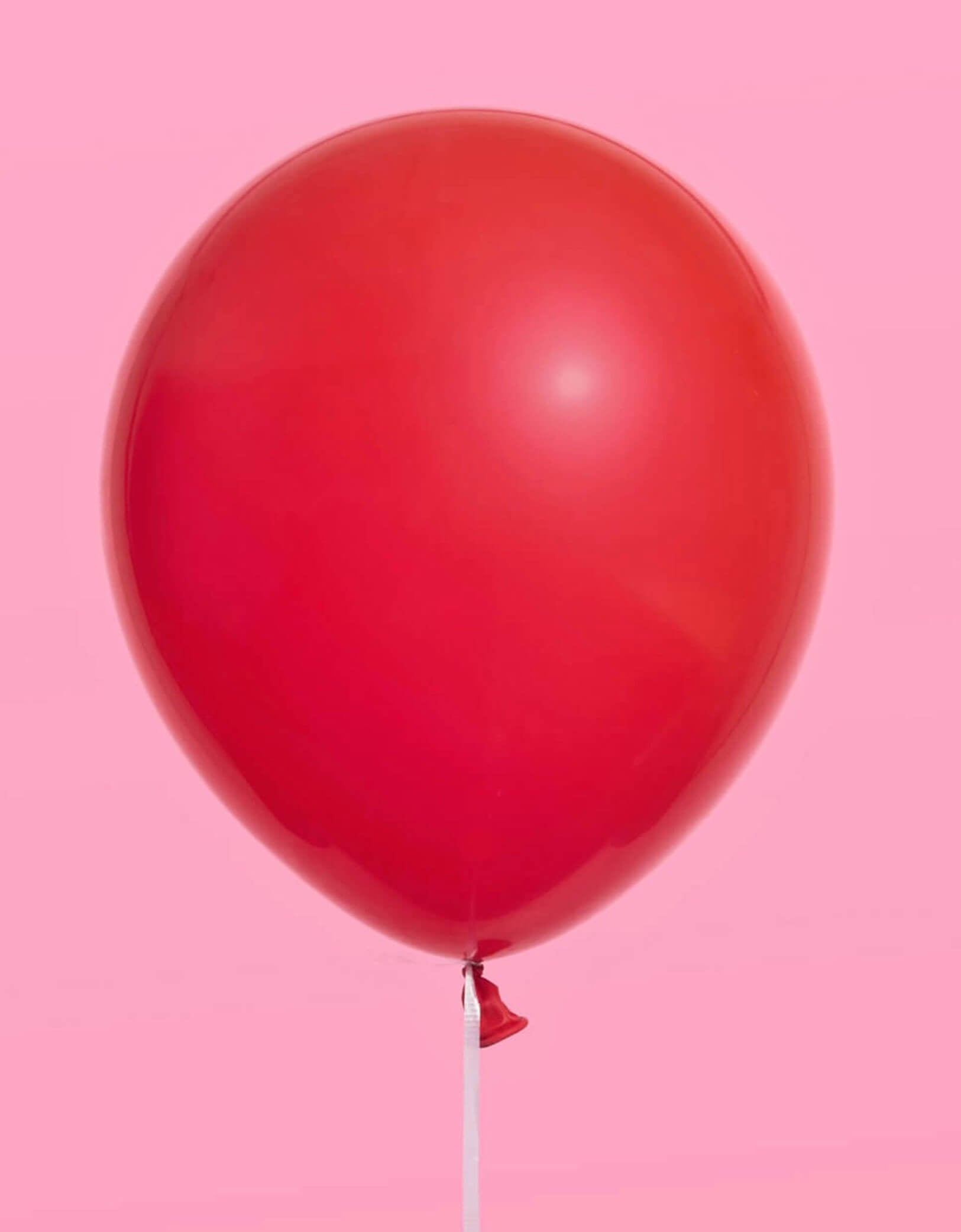 Momo Party's red Latex Balloon on a pink background.