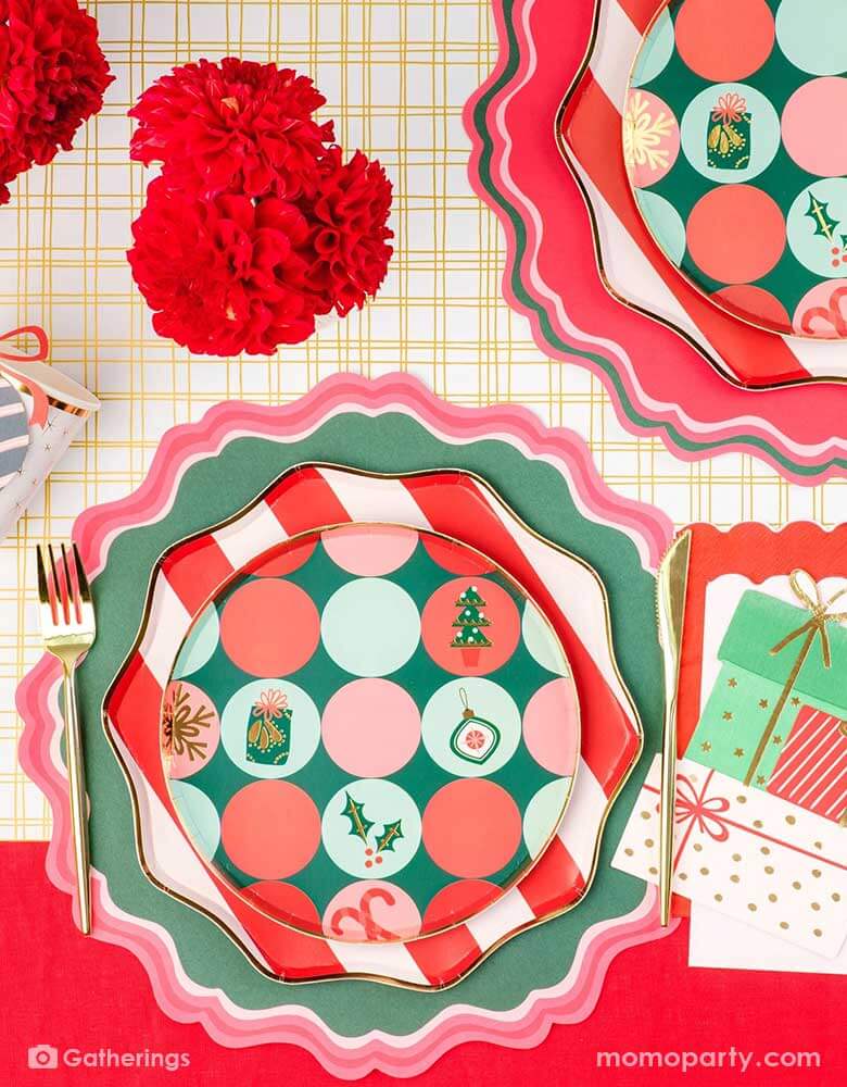 A festive Christmas party tablescape featuring Momo Party's Holiday tableware collection including red striped dinner plates and Christmas icon patterned side plates, with gifts shaped napkins and red and green placemats on the gold grid table runner, this makes a jolly table setting for this Holiday season.