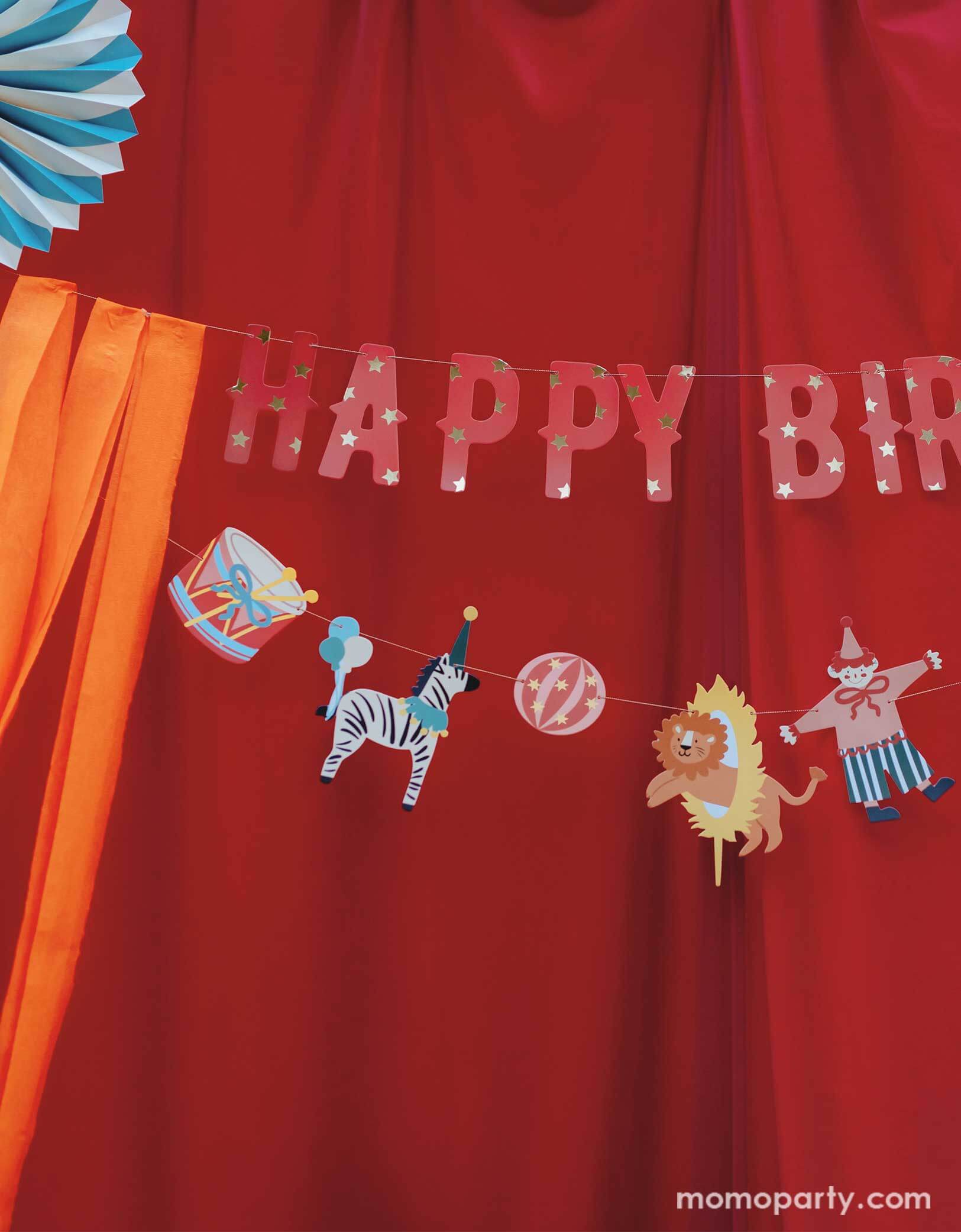 A vintage circus themed party backdrop with a red stage curtain decorated with Happy Birthday circus banner from Momo Party. Featuring fun and festive circus animals, bright orange streamers, and the classic "Happy Birthday" message, this banner will add a playful touch to any party. Bring the carnival to your birthday bash with this fun and colorful set!