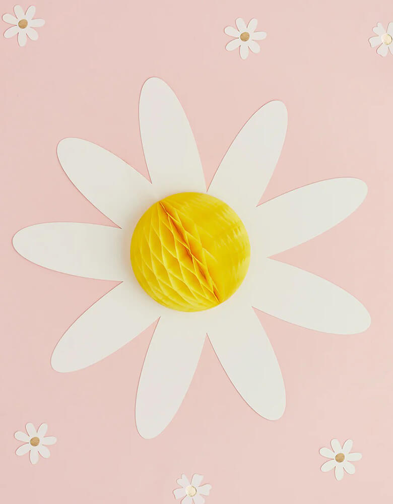 A close up of Momo Party's 13" Daisy Honeycomb by Hooty Balloo surrounding with daisy confetti  Comes in a set of 3 honeycombs, the perfect honeycomb decorations for any birthday, bbq or mother's day celebration! Take any celebration from basic to breathtaking with these versatile honeycomb decorations!