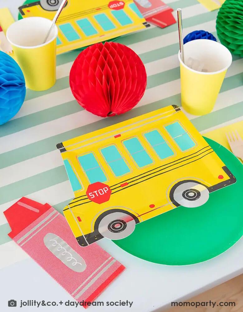 A festive back to school party featuring Momo Party's colorful school themed tableware including Daydream Society's school bus shaped plates, crayon shaped napkins with bright colored round plates and party cups. With festive colored honeycomb decorations on the party table, this gives a great idea and inspiration for a kid's back to school celebration.