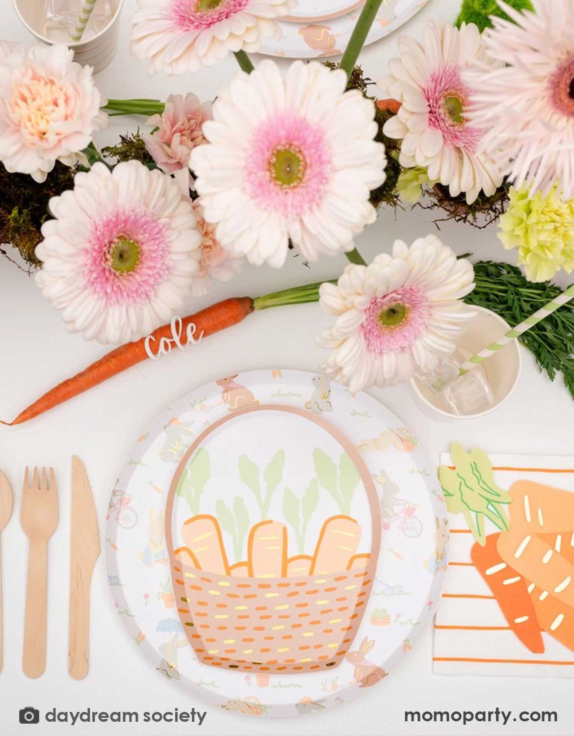 A overhead shot of a darling Easter-themed table setting with floral decorations, carrot basket shaped plates, carrot shaped napkins and matching utensils in a spring-inspired colors from Momo Party.