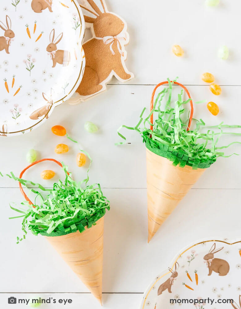 An Easter table features Momo Party's two carrot shaped treat bags by My Mind's Eye filled with Easter colored jelly beans. Around them are 10" x 10" brown rabbit scatter scallop plates and rabbit shaped napkins, makes this a great inspo for an adorable Easter table setting this spring.