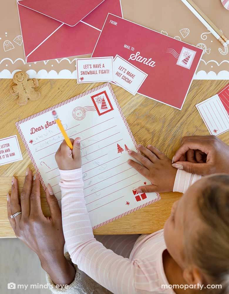 A girl writing her letter to Santa with her mom's help using Momo Party's Elf Letters to Santa stationary kit by My Mind's Eye. Each kit includes Included are 24 mini notes that your holiday friend can deliver to your loved ones, also included is one letter to Santa template that your holiday visitor can hand deliver to the big man when it is time for him to return home.