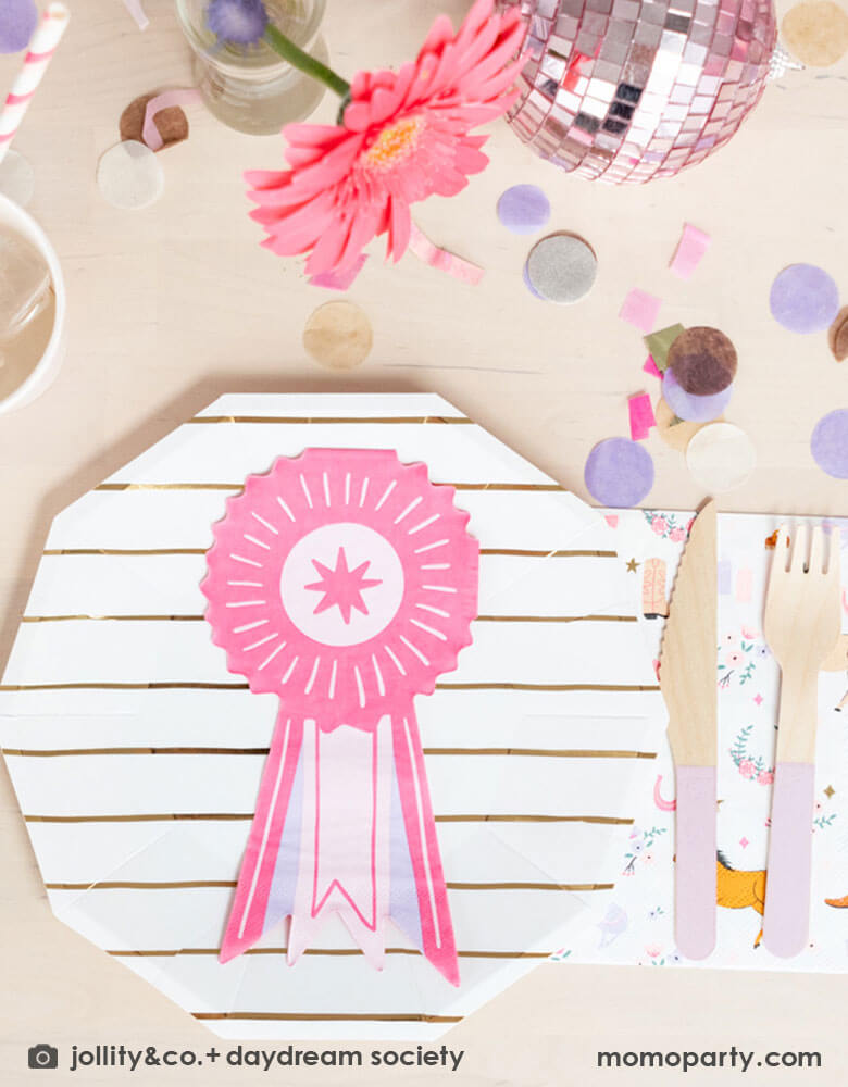 A girly pony/rodeo themed party table feature Momo Party's show ribbon shaped napkins, gold striped party plates, light pink wooden cutlery set and cowgirl motif large napkins by Daydream Society. Around the tableware there are some lilac and pink paper confetti spread-out and a small pink disco ball decoration with a pink sunflower, making this an adorable inspiration for girl's First Rodeo first birthday celebration or an adorable derby theme party for pony-loving girls!