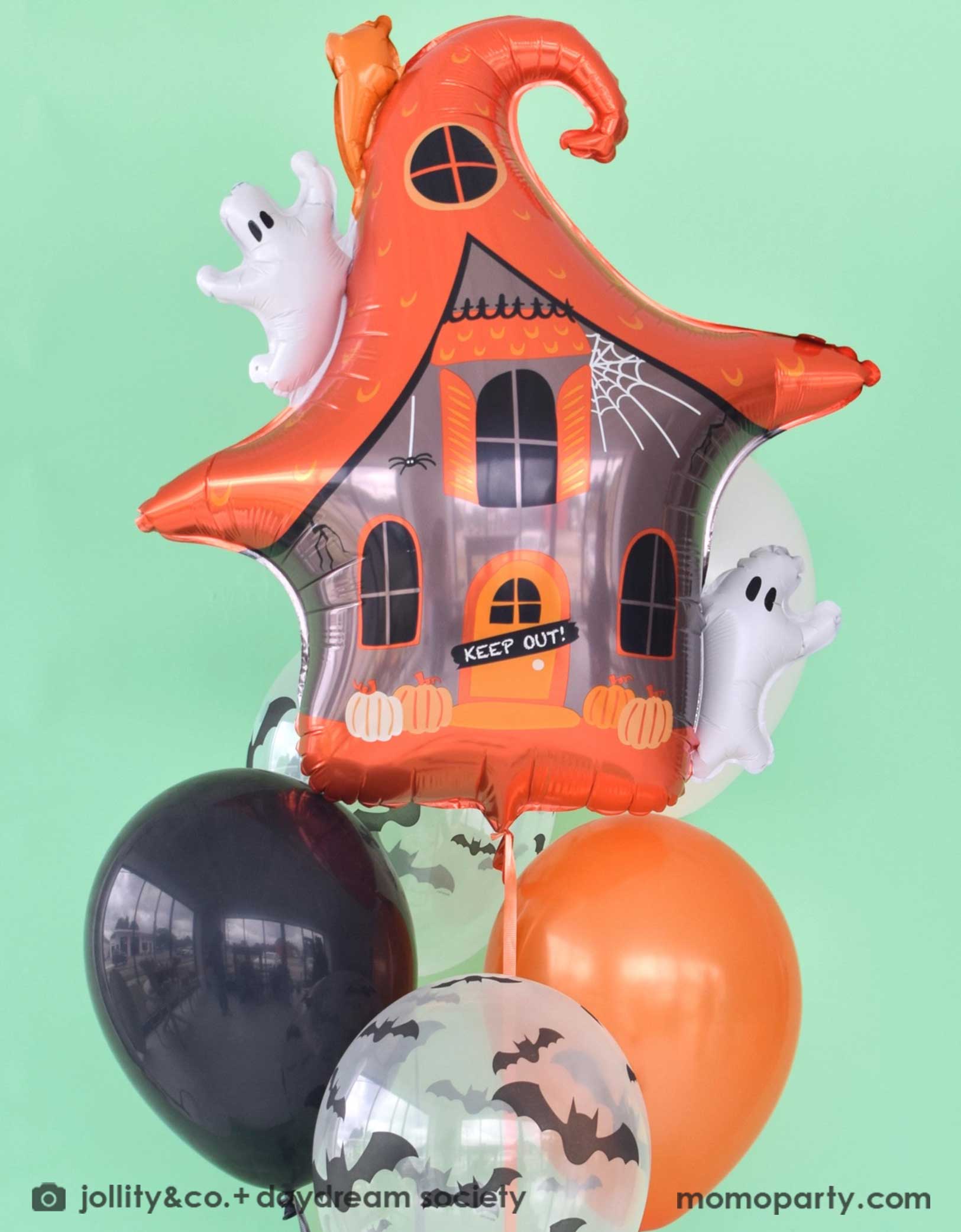 Momo Party's 23.4" x 24.8" Halloween themed balloon shaped like a haunted house with ghosts by Daydream Society with a mix of Halloween themed latex balloons in orange, black and bat design on a mint green background.