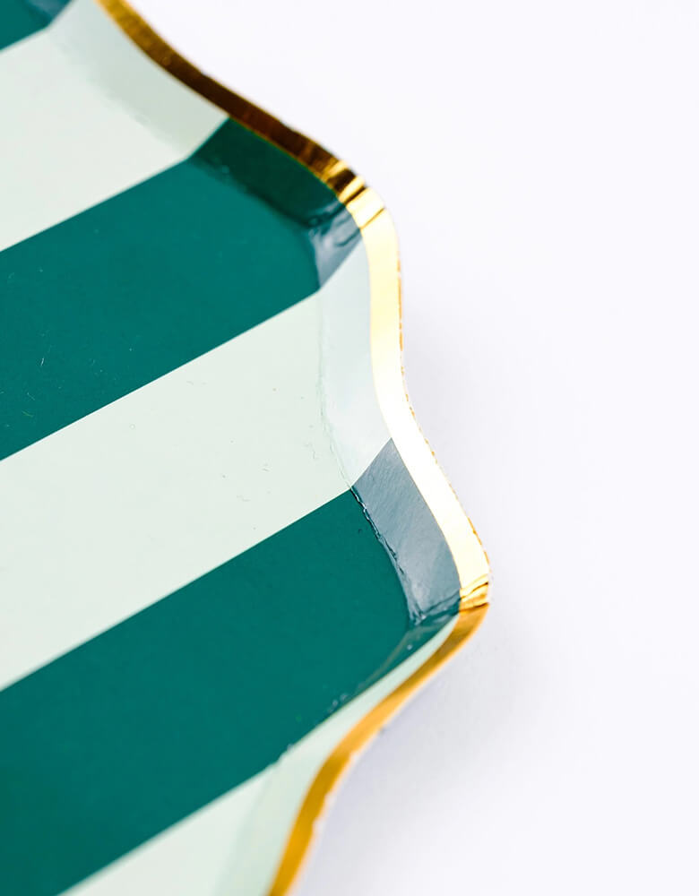 A close up shot of Momo Party's 8.5" Holiday Stripes Dessert Paper Plates by Gatherings. Comes in a set of 8 plates, made with eco-friendly FSC Mix paper, these vibrant and stylish plates with gold foil edge are the perfect addition to any holiday table, and their durable design ensures they can handle any dessert or appetizer. Make your holiday celebrations even more special with these delightful plates!