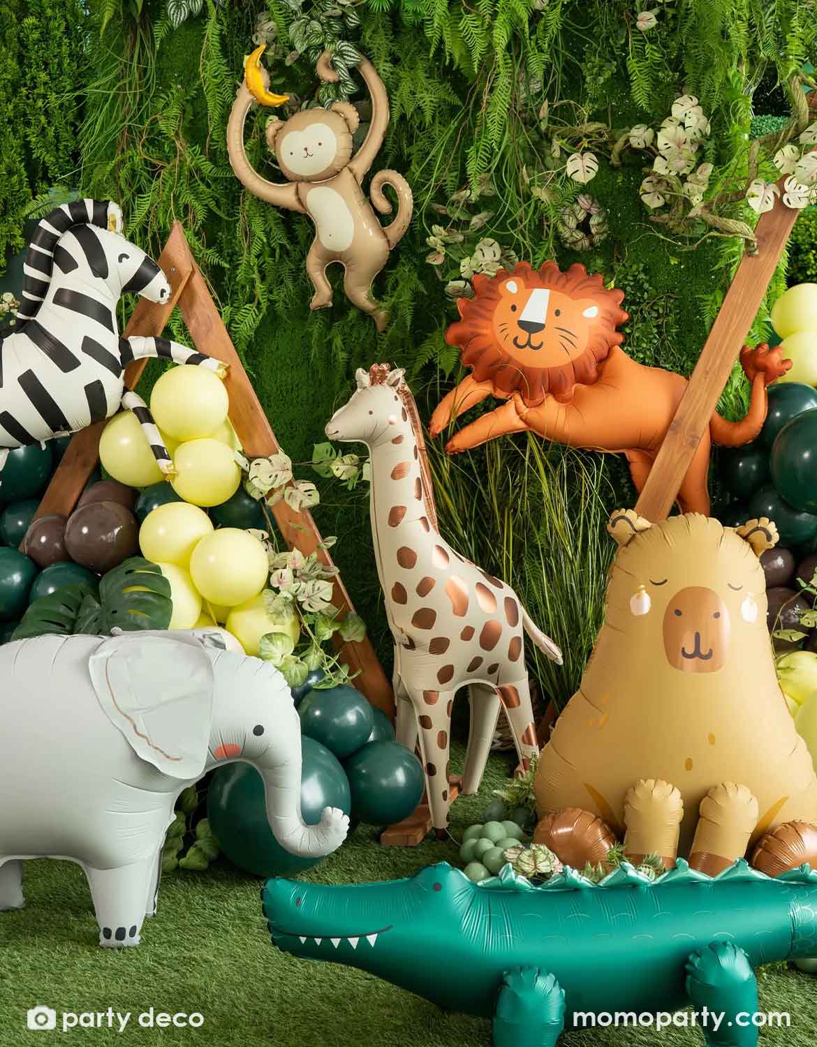 A collection of jungle/safari animal themed foil balloons from Momo Party featuring a zebra, monkey, lion, giraffe, elephant, capybara and crocodile against a jungle decorative backdrop along with some green latex balloon garland, making this a perfect set up for kid's jungle/safari themed birthday party, be it a "Wild One" first birthday party, a "Two Wild" second birthday party or a any adventure themed celebrations.