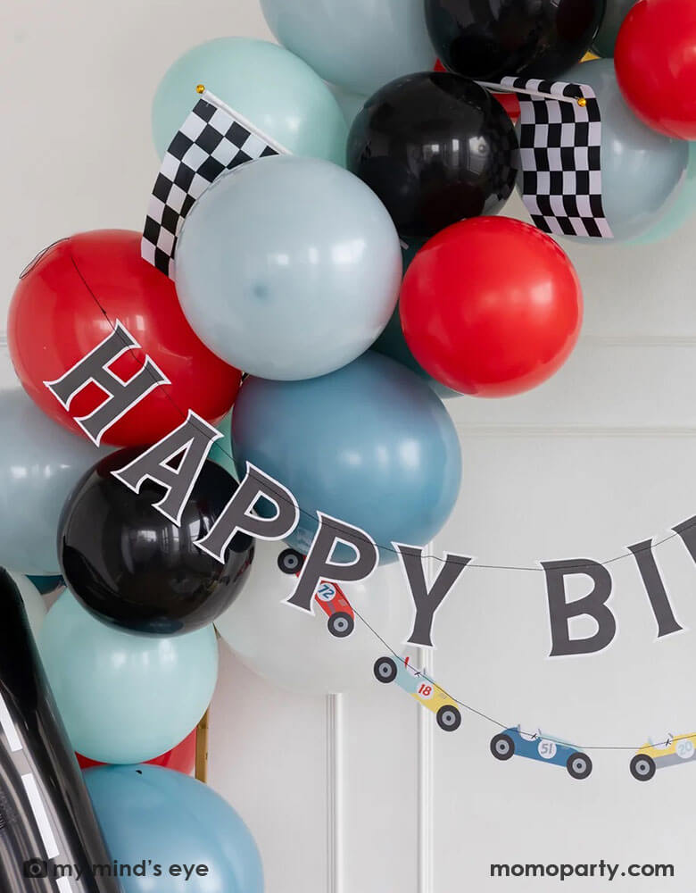 A kid's race car themed birthday party decoration set up features Momo Party's 4ft & 6ft  Miles Per Hour race car happy birthday banner set, a balloon garland in dark blue, light blue, red and black colors adorned with checkered race car flags, making this a perfect inspo for modern kid's car themed parties, be it a "Fast One" first birthday party, a "Two Fast" second birthday party, "speed limit 3" or "grand 3" third birthday or a "Need Four Speed" fourth birthday bash.