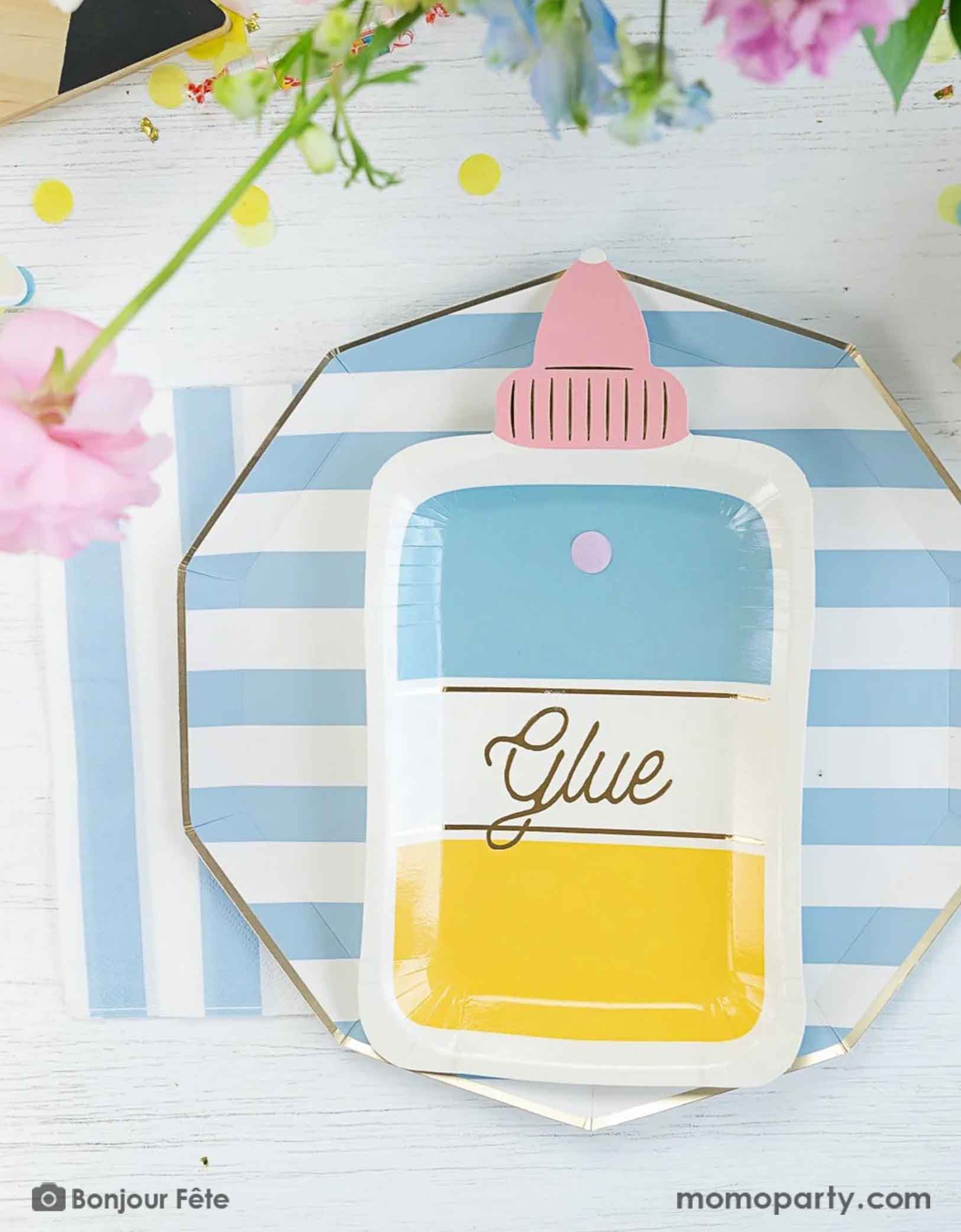 An overhead shot of a school themed tablescape featuring Momo Party's sky blue striped dinner plates and napkins paired with glue bottle shaped plate, which makes a great inspiration and idea for a school themed celebration or a back to school/first day of school party for kids.