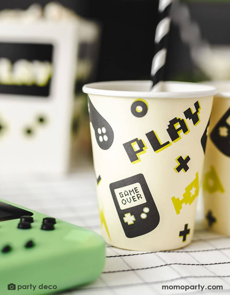 A close up shot of Momo Party's 7.4 oz Video Game Party Cups by Party Deco. Designed with a game device motif pattern with SUPD labelling. pixelated word "PLAY" on it, this set of 6 party cups is perfect for any gamer.