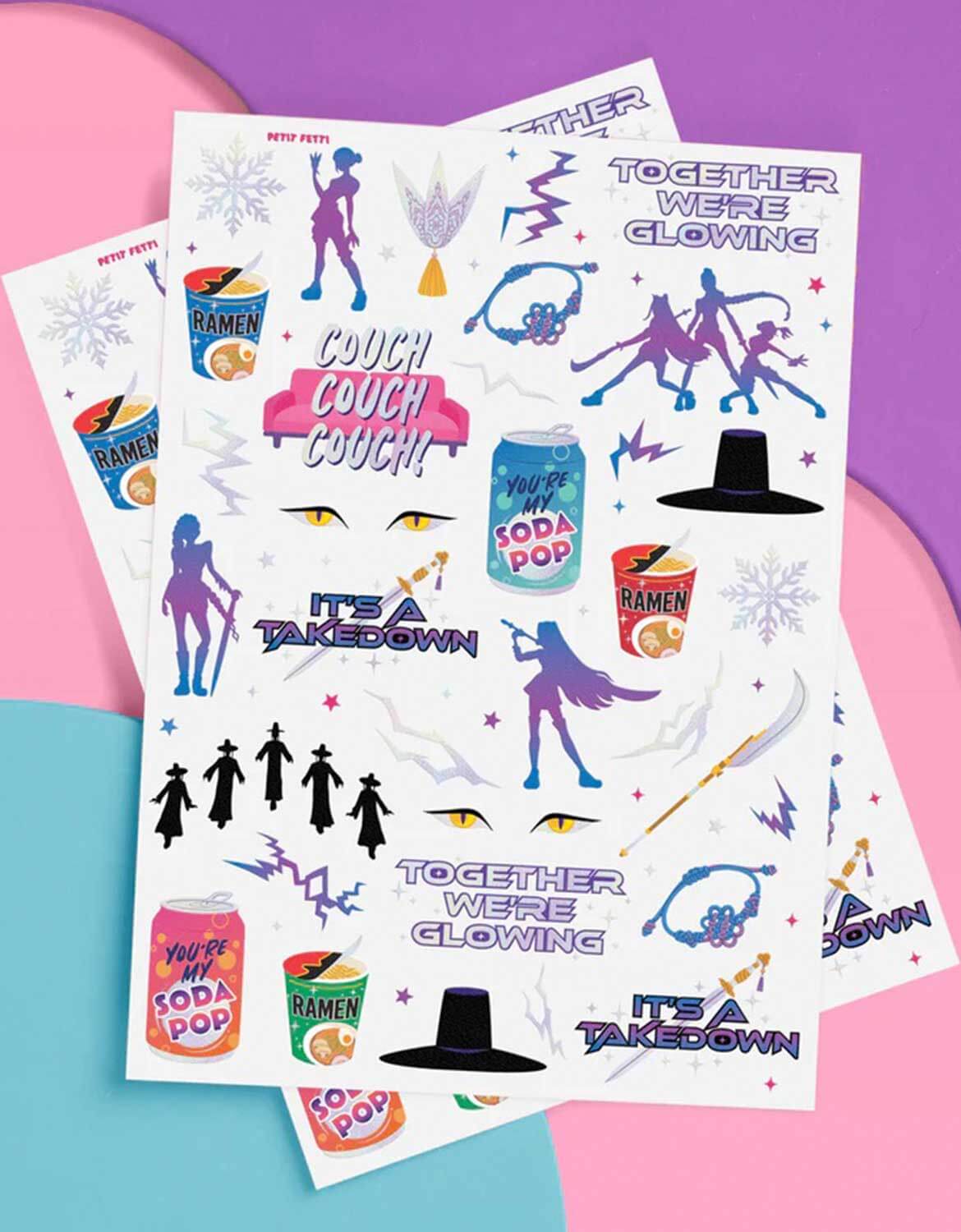 Momo Party's Kpop Demon Hunters themed temporary tattoos sheets of two with colorful graphics including dancing figures, soda pop cans, lightning power symbols and texts by Xo, Fetti on a pink, blue and purple background.
