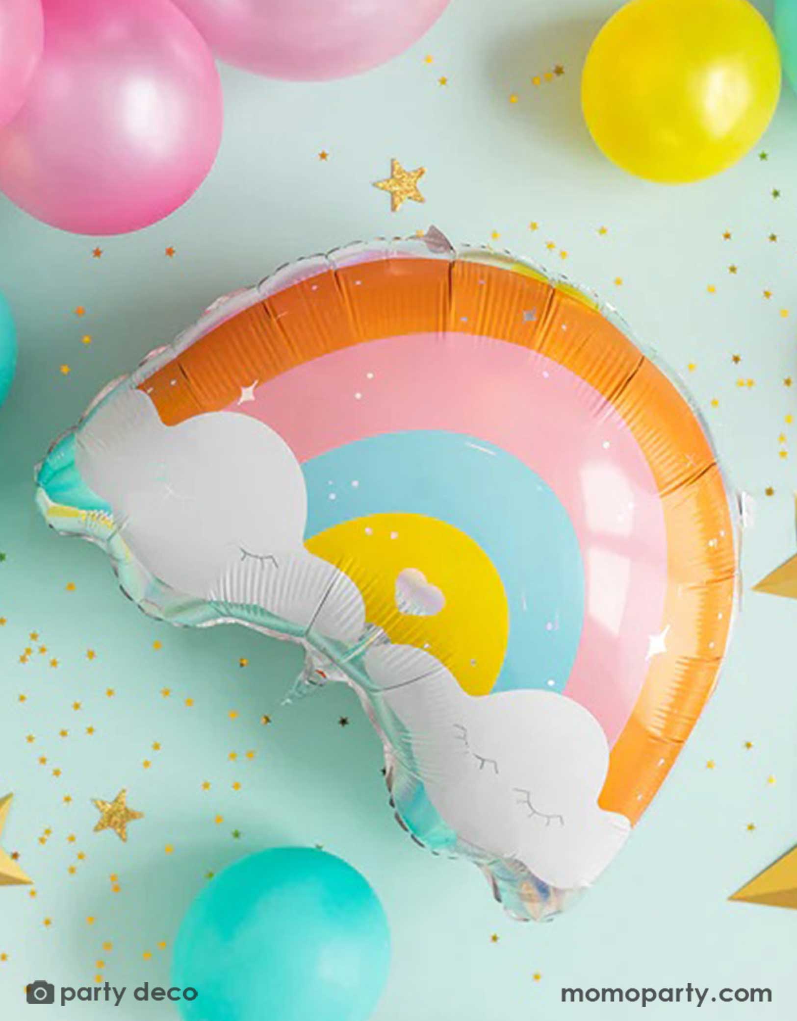 Momo Party's 21.5" colorful rainbow-shaped foil balloon with colorful latex balloons around it and gold star shaped confetti spread out on a light blue background.