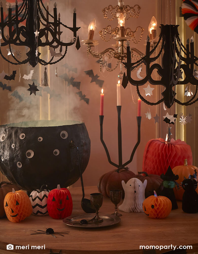A magical Halloween party table featuring Momo Party's Halloween paper decorations including black chandelier, honeycomb Halloween characters and a huge cauldron decorated with googly eyes. All makes a great inspiration for a witch themed Halloween bash.