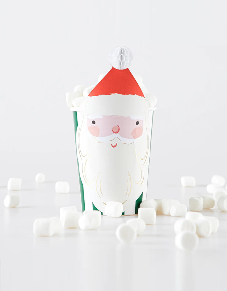 Momo Party's 9oz Christmas Santa honeycomb party cups in green stripes by Meri Meri. Next to the cup there are marshmallows, make these cups perfect for Holiday hot cocoa hot chocolate for kids this Holiday season. 