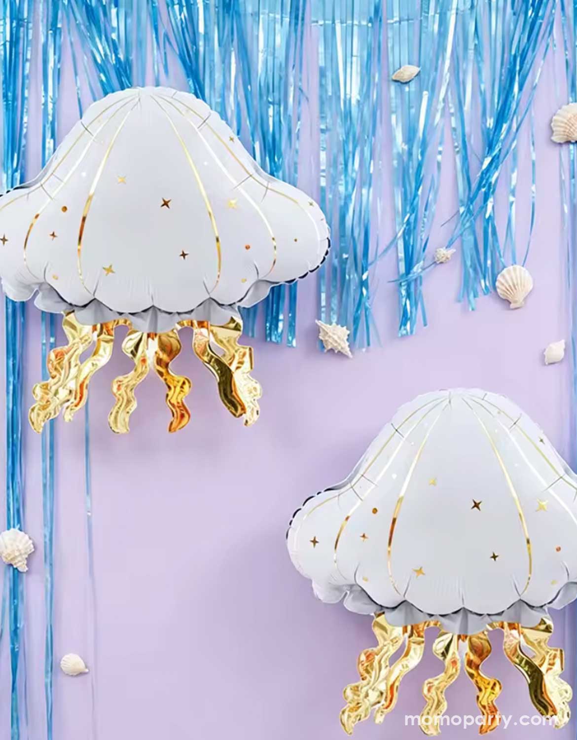 Two Momo Party's 21" Mermaid Party Jellyfish Foil Balloon floating on a lilac wall backdrop with blue foil fringe decoration hung above - a perfect decoration for kids mermaid or under the seam birthday parties.
