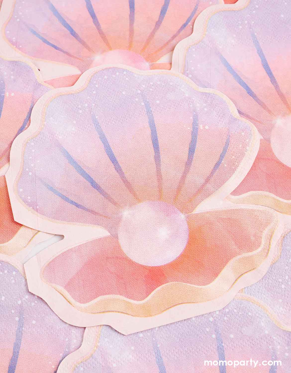 Multiple Momo Party's 6.25" x 5.5" pastel-colored shell shaped napkins with a pearl inside staggered.