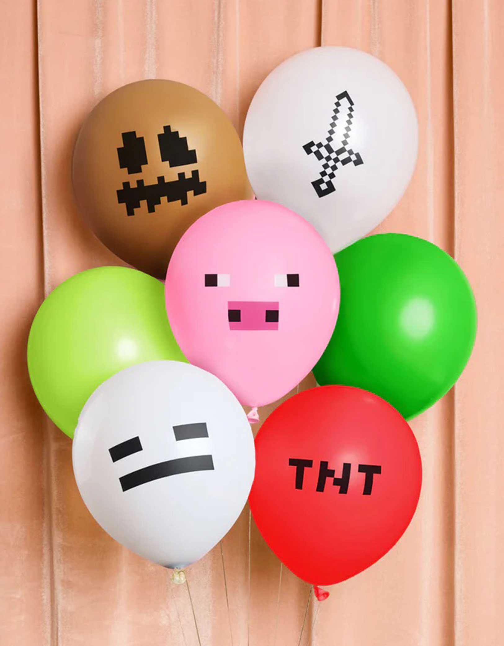 The 11" Minecraft Pixel balloon bunch from Momo Party featuring various colors of latex balloons with pixelated faces and 'TNT' text on a pink curtain background.