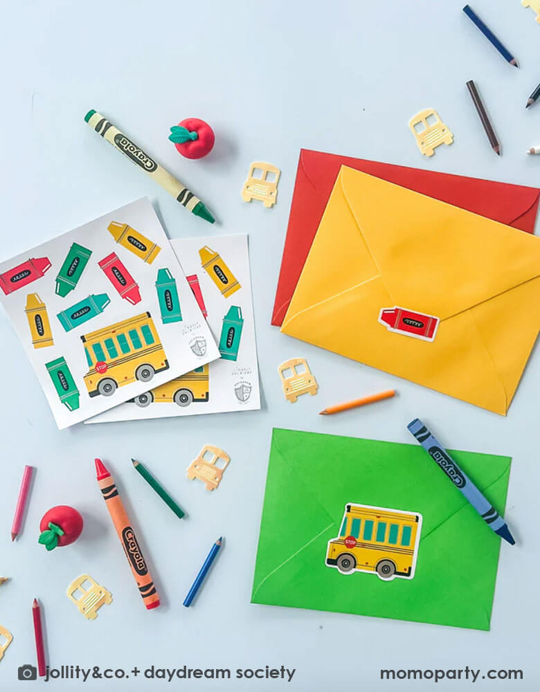 A table filled with school supplies and envelopes and Momo Party's school days sticker set featuring school bus shaped and crayon shaped stickers in bright colors. This sticker set is perfect to get your little one excited for the first day of school!! Use to decorate notebooks, classroom favors or teacher gifts. Plus they're perfect for decorating presents or used as party favors.