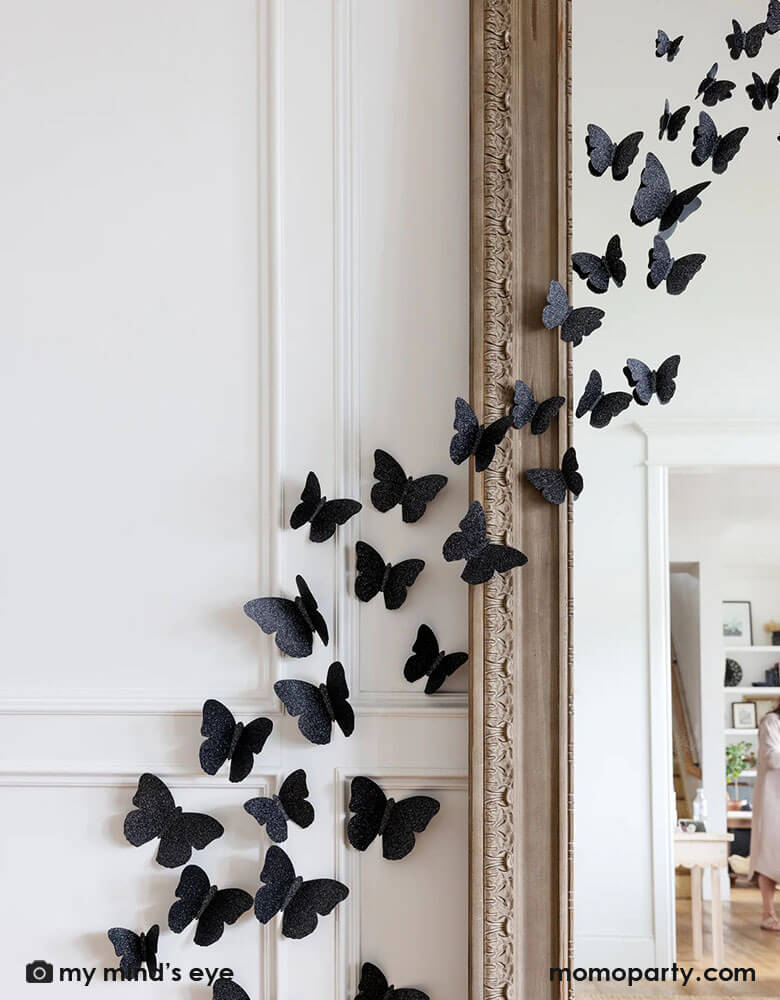 A large full body mirror decorated with Momo Party's Halloween Wall Black Glittered Butterflies Decorations by My Mind's Eye. These die cut and dimensional butterflies are the perfect way to add some fright to your home this Halloween.