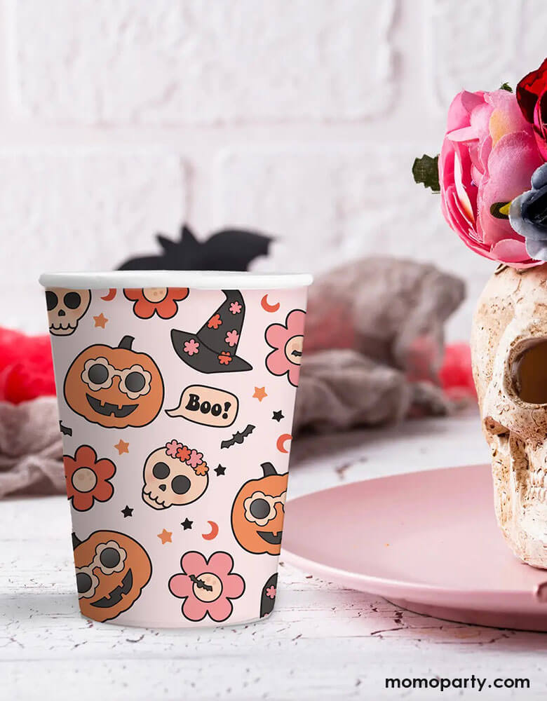 Momo Party's 9 oz Groovy Halloween party cups by Ellie's Party on a Halloween party table decorated with floral skull and Halloween bats in the back.