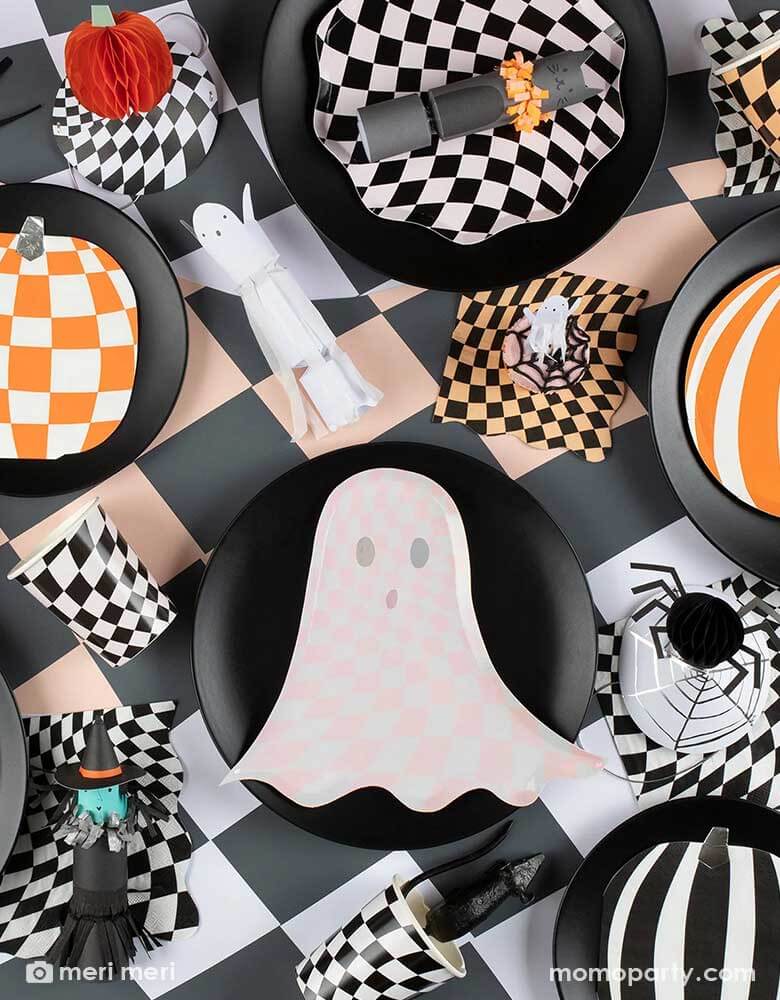 A spooky yet stylish tablescape featuring Momo Party's Halloween wavy checkered plates, napkins and cups by Momo Party, in the middle of the table is the pink ghost shaped plate with chic checkered pattern, it creates a fun inspiration for kid's not-so-spooky Halloween celebration.
