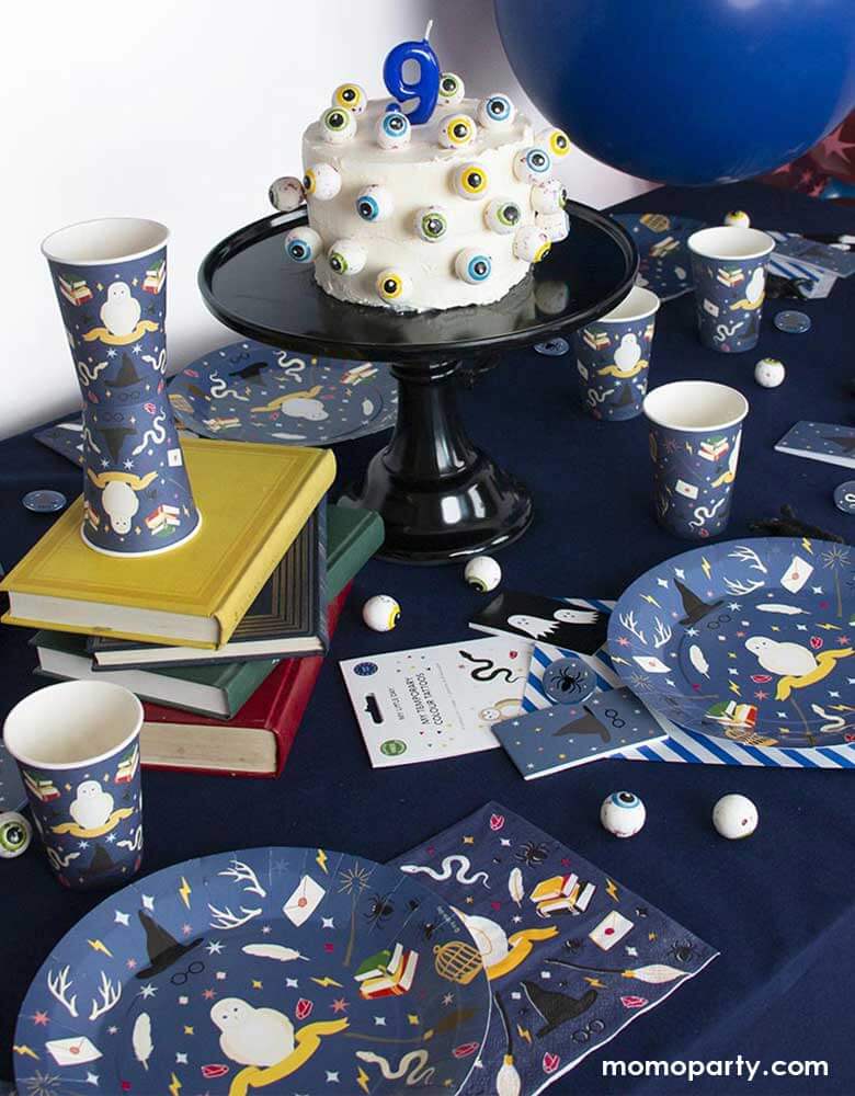A Harry Potter wizard themed party table featuring Momo Party's wizard party supplies including party plates, cups, napkins and temporary tattoos. With a cake decorated with spooky eyeballs as the centerpiece and spell books in the middle, this makes a great inspiration for kid's Harry Potter themed birthday party or Halloween bash!
