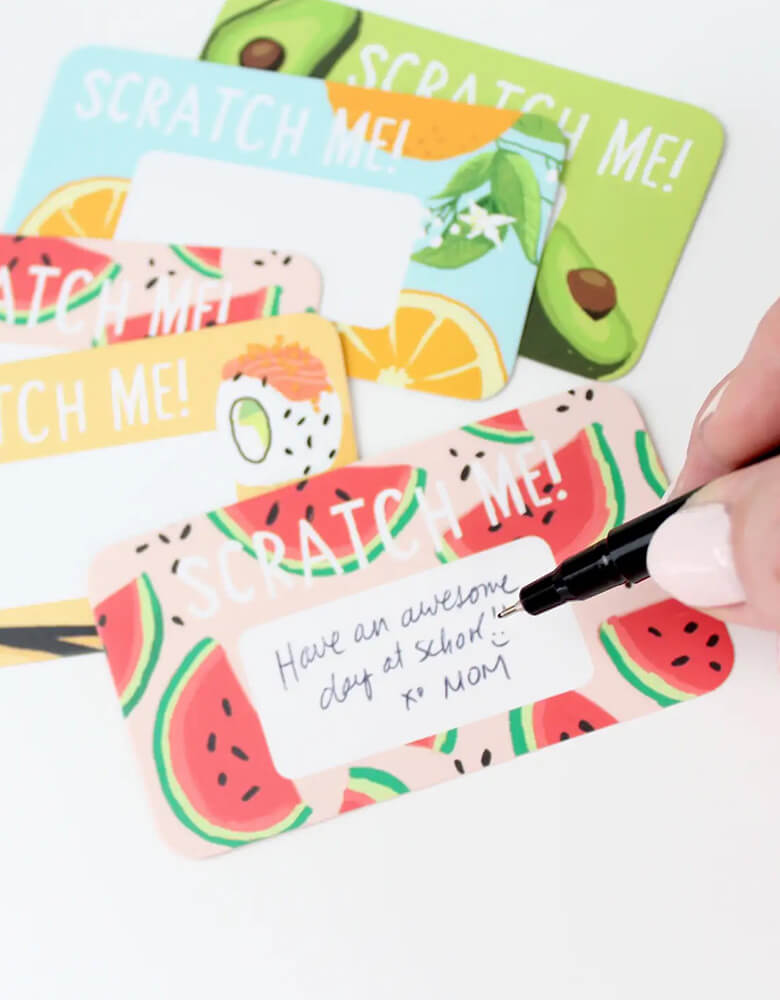 Momo Party's Scratch-off Lunchbox Notes by inklings Paperie. Kit included 24 scratch off cards with food illustrations including watermelon, burgers, sushi, fruits, avocado. Each set includes 24 stickers, in a clear plastic box. Simply write your own special handwritten message in the designated area, cover it with the scratch-off sticker provided, and scratch to reveal your hidden message! These tiny notes are the perfect size to slip into a lunch bag or coat pocket of someone special.