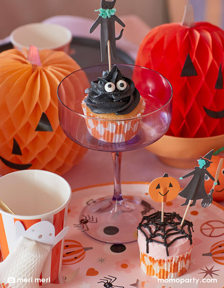 A pink Halloween party by Meri Meri featuring pumpkin honey comb decorations, Halloween character cupcake kit including Halloween toppers like witches, pumpkins, black cats, Halloween character dinner plates and Halloween honeycomb party cups. Perfect inspo for a kid's friendly not-so-spooky Halloween party!