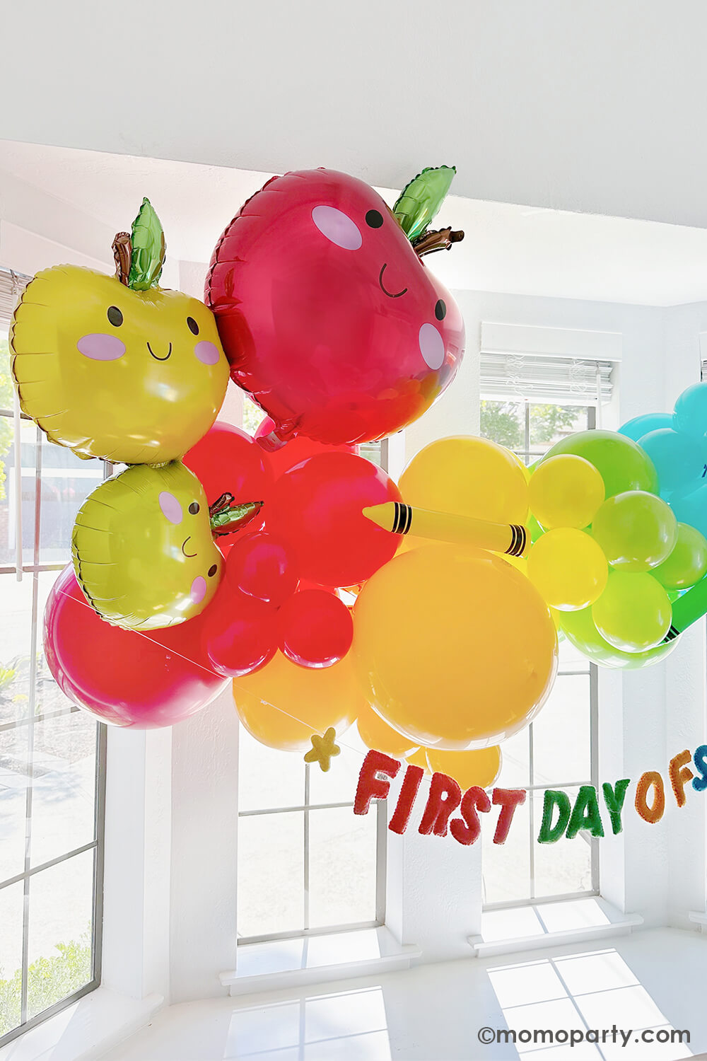 A bright, modern kitchen bay window in the morning decorated with Momo Party's first day of school balloon garlands in fun and bright colors. Underneath is a "first day of school" felt banner by Studio Pep. Along with the adorable apple stacker foil balloon, this makes a great back to school decoration idea and inspiration for any school themed celebration!