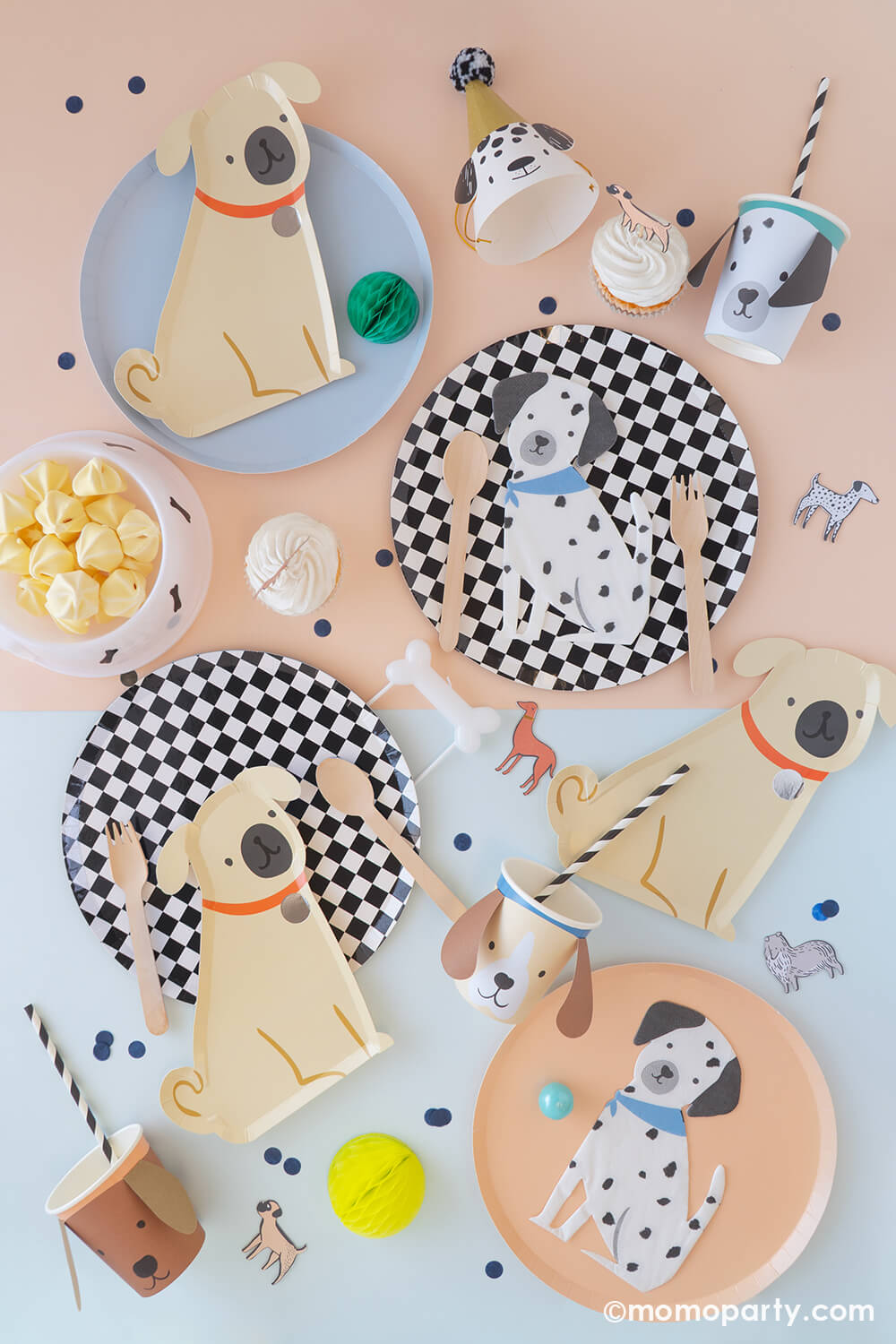 A soft color table with light blue and light peach colored tablecloth filled with Momo Party's dog themed party supplies including 10" black and white checkered round dinner plates, 8.5" x 9" pug dog shaped plates by Meri Meri, Dalmatian shaped napkins, 3D dog party cups and dog shaped party hats, along with yummy treats topped with dog themed cake toppers and bone shaped candle, it makes a great inspo for kid's puppy themed birthday party or a party for your four legged friend!