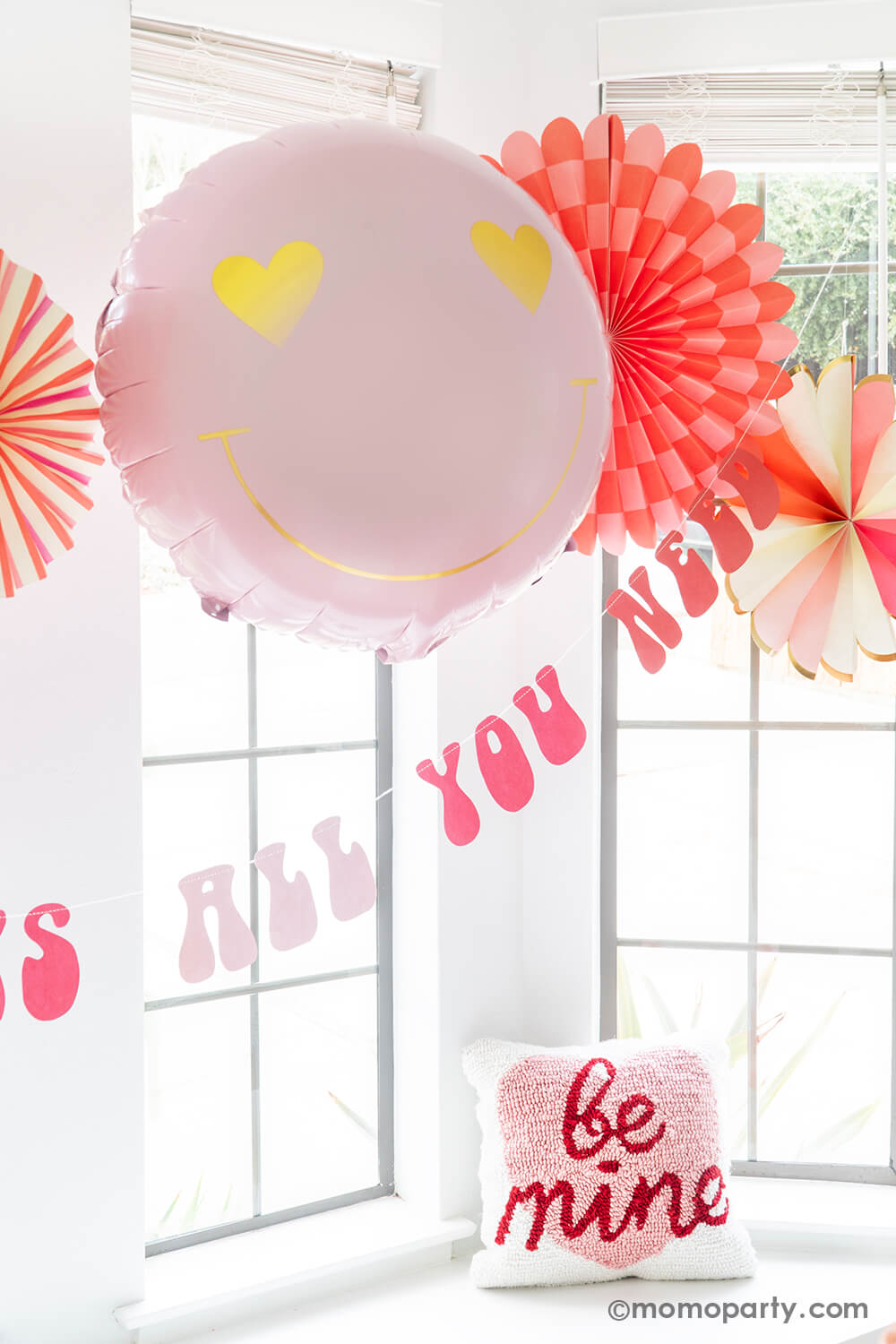 A close-up of Momo Party's Groovy Valentine's Day Party decorations, featuring My Mind's Eye Heart You Paper Fan Set with both round and heart-shaped paper fans. Paired with a Heart Eyes Love Foil Balloon and a retro-style Love Is All You Need Banner underneath, these products offer an easy and quick setup for the perfect Valentine's Day party or Groovy themed Birthday Party, or Any romantic occasion
