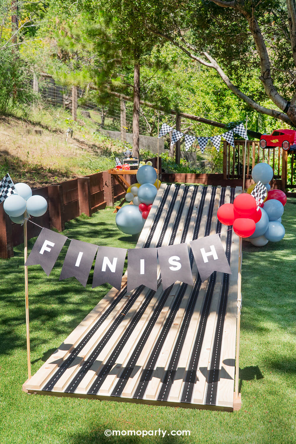 A kid's Disney Cars themed birthday party race track activity set up by Momo Party. This vroom vroom wooden race track for endless fun was decorated with festive balloons adorn with the race car checkered flags from Momo Party.  A perfect decoration inspo for boy's race car themed birthdays or Lightning Mcqueen themed parties.
