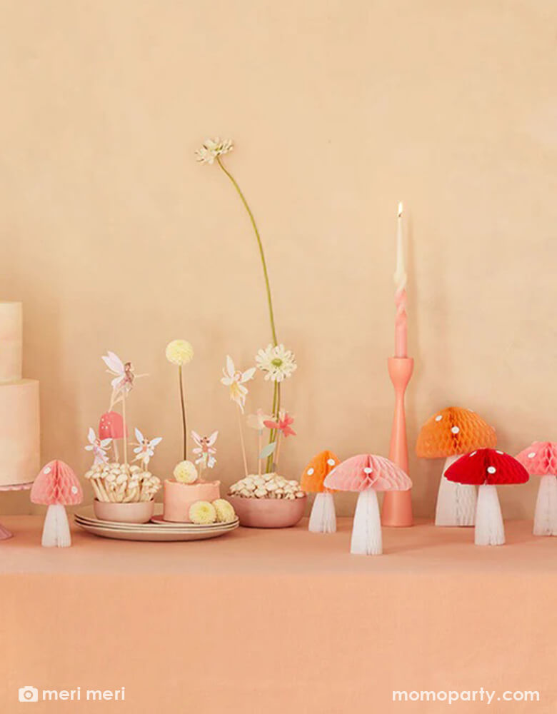 A whimsical fairy themed birthday party table featuring Momo Party's mushroom honeycombs and fairy cake toppers. A few small cupcakes are topped with fairy cupcake toppers and cake topper and adorn with buttercream flowers, makes this a simple yet whimsy party inspo for kid's forest fairy themed party.
