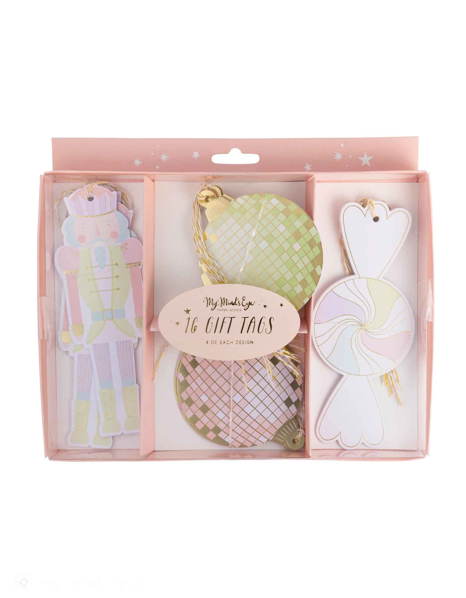 The pink package of Momo Party's set of pastel colored Christmas themed gift tags of 16 including the designs of a Nutcracker, disco ball, and candy with gold strings by My Mind's Eye on a white background.