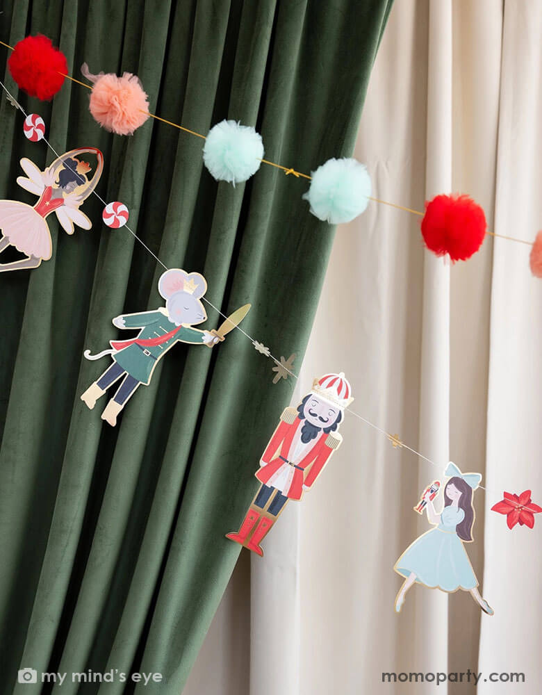 A close up of Momo Party's 6' Nutcracker party banner set by My Mind's Eye. Featuring charming nutcracker icons, this banner set is sure to bring joy and merriment to any room. Hang it on your mantel, above your doorway, or anywhere else you want to add a festive touch. These banners are hung next to a velvet stage curtain in green and beige colors, adding a festive touch to your Holiday celebration.