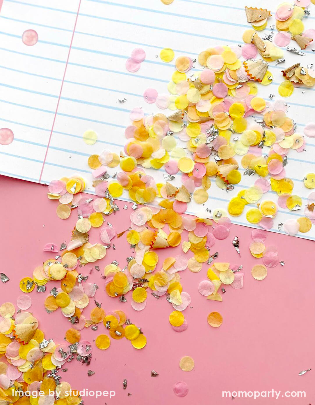Momo Party's pencil inspired colorful confetti  in light pink and yellow scattered on pink paper with a notebook in the background. Perfect for kid's back to school or end of school celebration!