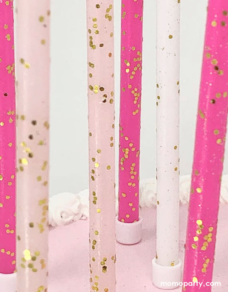 A closer look of the details of Momo Party's Pink Tones Gold Glitter Candle Set by Party Partners on the cake. This enchanting set features candles in light pink, hot pink, and white adorned with a touch of gold glitter. Complete with candle holders for seamless placement, these whimsical candles add a magical touch to any event. Ideal for princess party or girly celebrations of any kind, these candles bring a touch of elegance and charm.